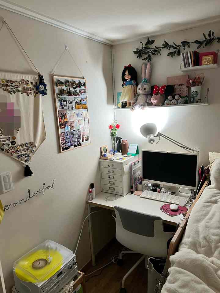 Bright white and brown toned small room home office space featuring desk, chair, wall lamp, and decorative items for cozy work environment