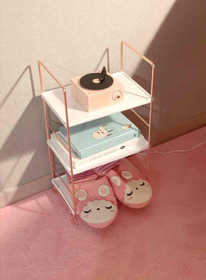 Cozy, minimal space with pink-toned flooring and a small white side table featuring a retro turntable and plush slippers