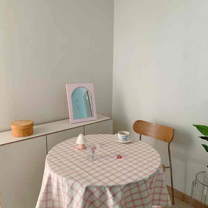 Living room with white walls, wooden chair, and pink checkered tablecloth on round table