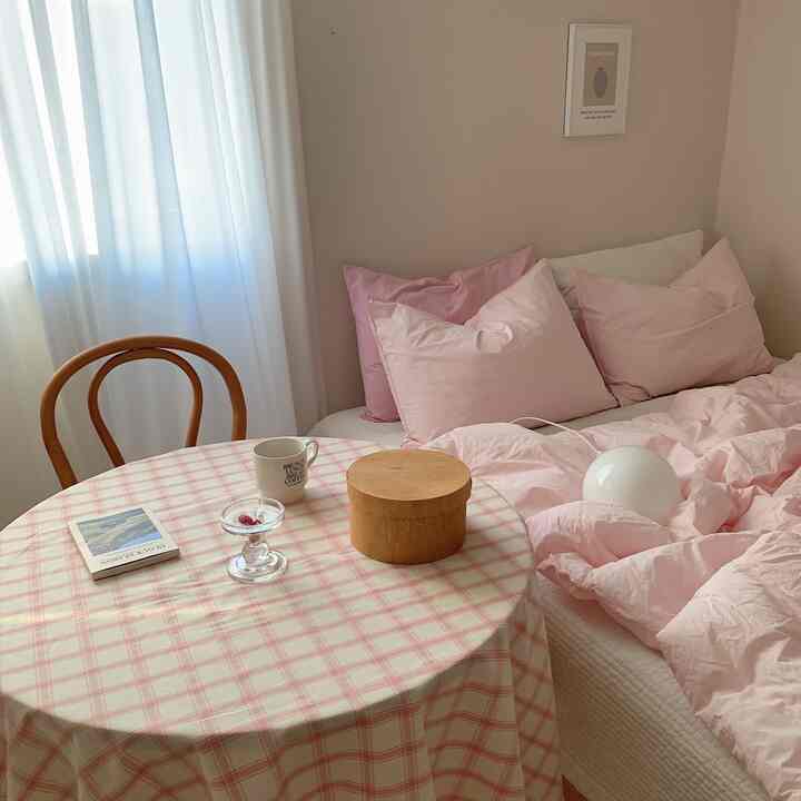 Cozy master bedroom in warm beige and pink tones featuring pink bedding and wooden chair with natural lighting