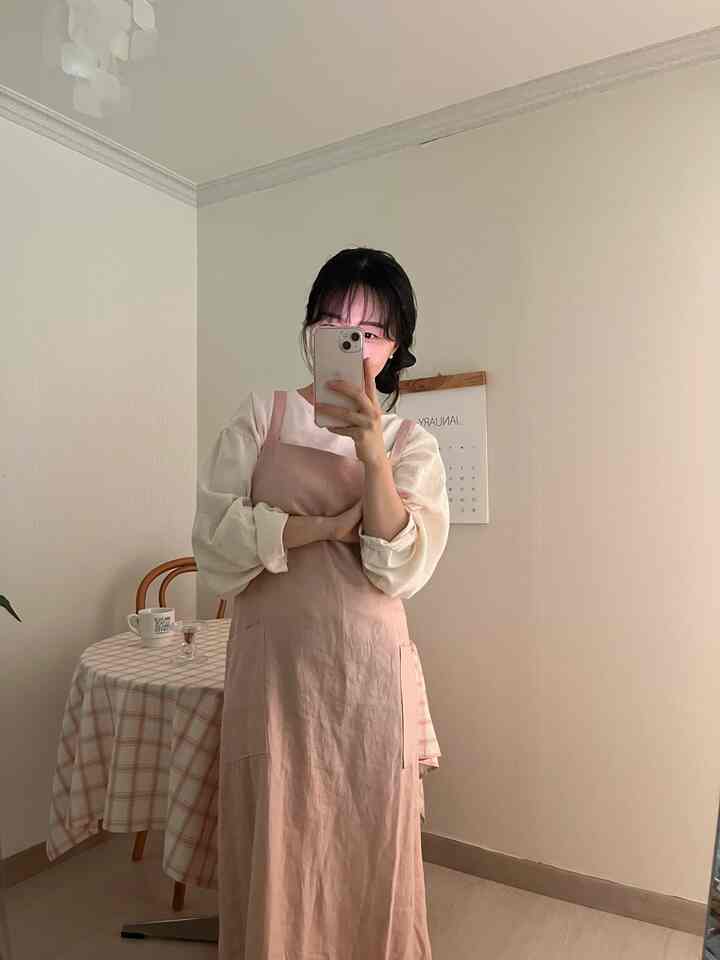 柔らかいピンクのエプロンとチェック柄のテーブルクロスが配置されたナチュラルな雰囲気のダイニングルーム