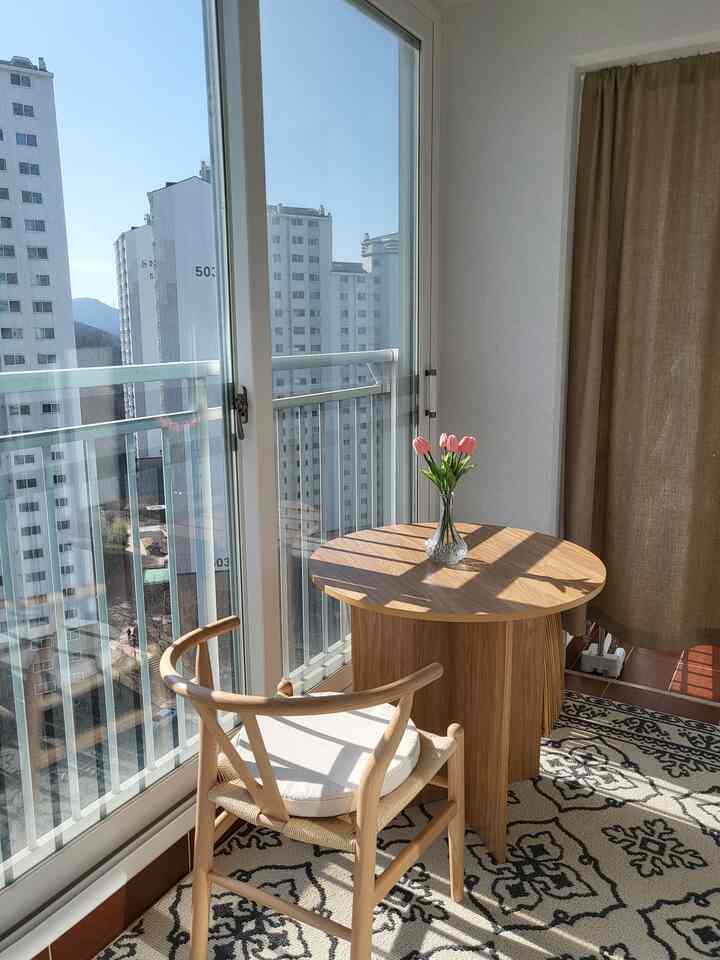 A natural-toned veranda home cafe featuring wooden furniture and fresh tulips, bathed in warm natural lighting for a cozy atmosphere