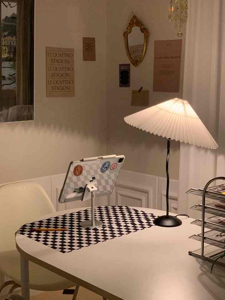 White and black toned home office space with a pleated lamp illuminating a desk, creating a quiet nighttime work environment