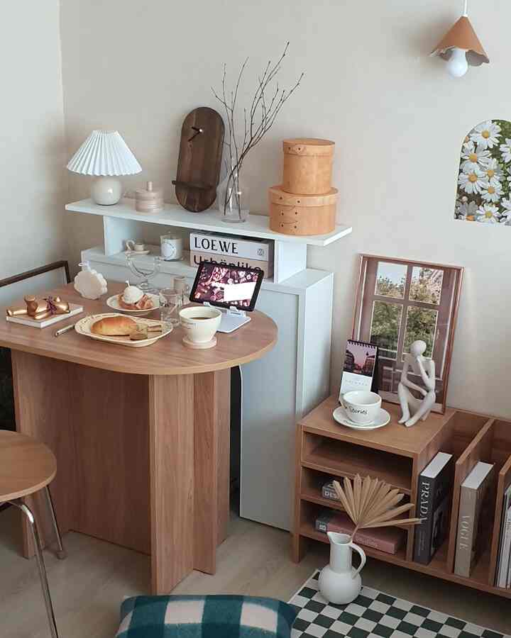 A cozy living room with beige walls and wood-tone dining table, featuring home cafe accessories and warm lighting