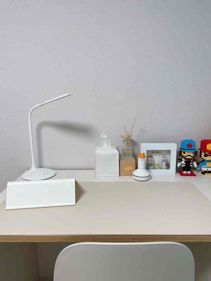 ナチュラルトーンの子供部屋の机スペース、シンプルなワイヤレススタンドと遊び心のあるオブジェが配置された清潔感のあるインテリア