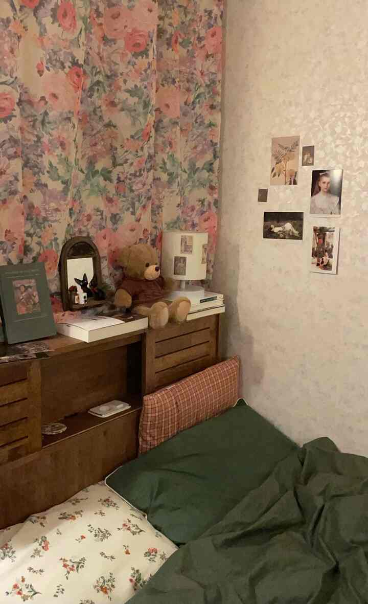 Vintage and retro bedroom space featuring floral curtains, brown wooden furniture, and cozy green bedding for a warm atmosphere