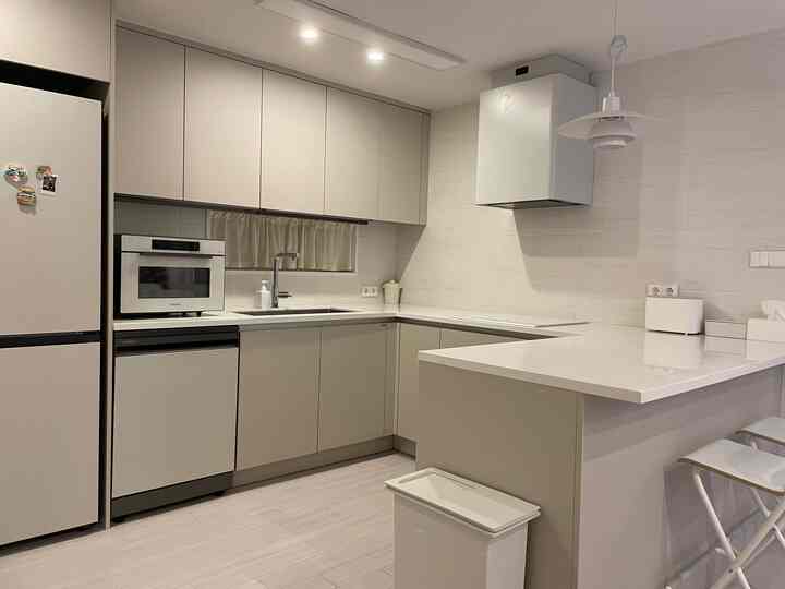White and natural tone kitchen featuring a U-shaped sink with an island home bar, presenting a simple and modern kitchen interior