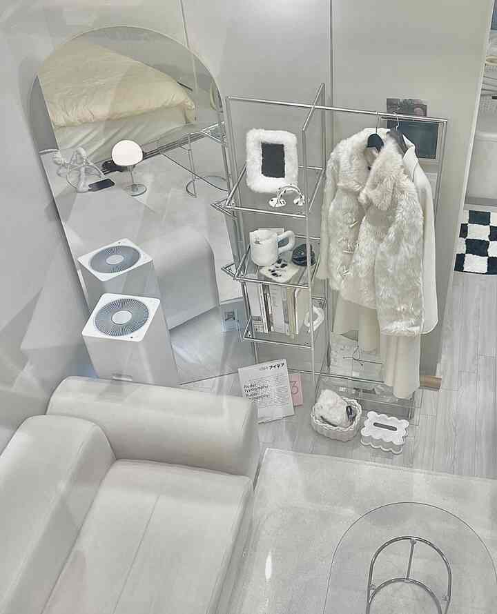 Bright white-toned living room featuring a modern sofa, large arched mirror, and metal shelf in a natural modern interior
