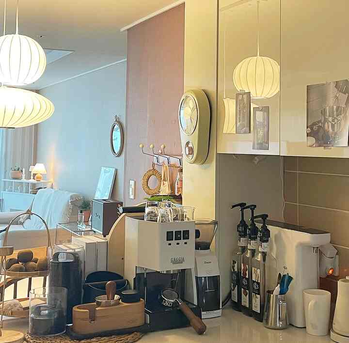 A modern kitchen and home cafe space featuring white and wood tones, pendant lights, and tidy furniture arrangement creating a cozy atmosphere