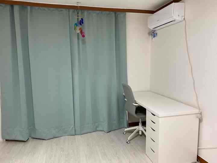 Minimal home office space with light green curtains and white desk in a single household room