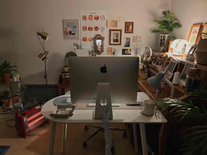 Natural-toned home office with white desk and brown dresser, featuring a computer centered