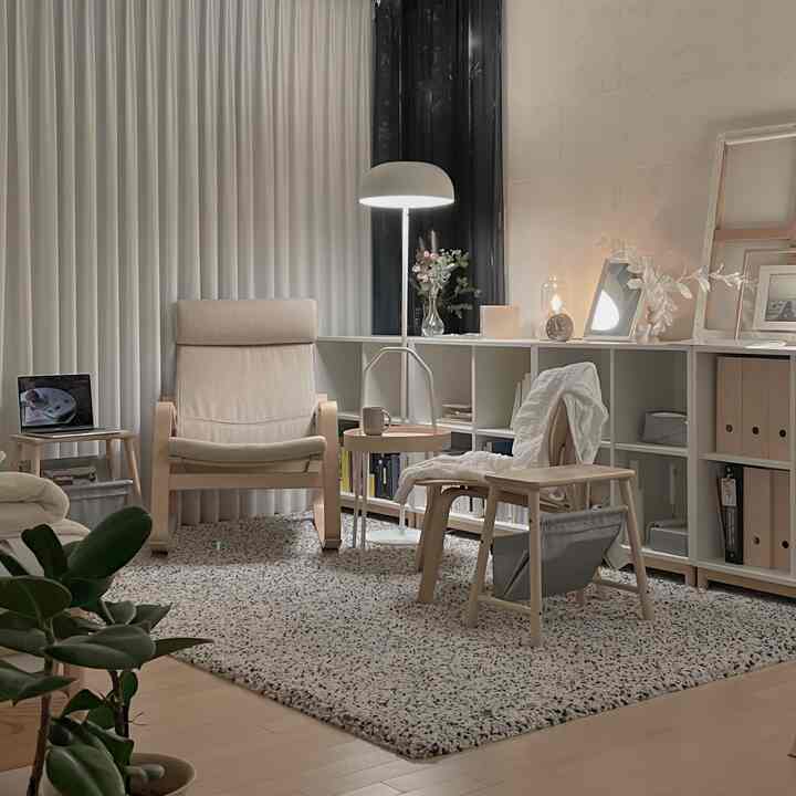 Natural wood tone and white study-like living room featuring armchairs and a large rug, creating a cozy atmosphere