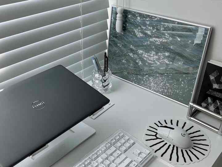 A compact home office desk space in white and blue tones, featuring a laptop and mechanical keyboard neatly arranged