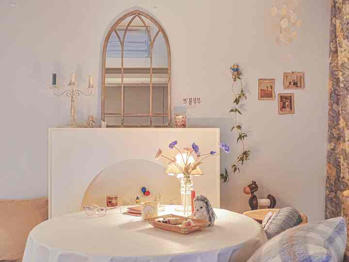 ホワイトとベージュのトーンでまとめられた、アンティークな装飾と丸テーブルが配置された雰囲気のあるダイニングルーム