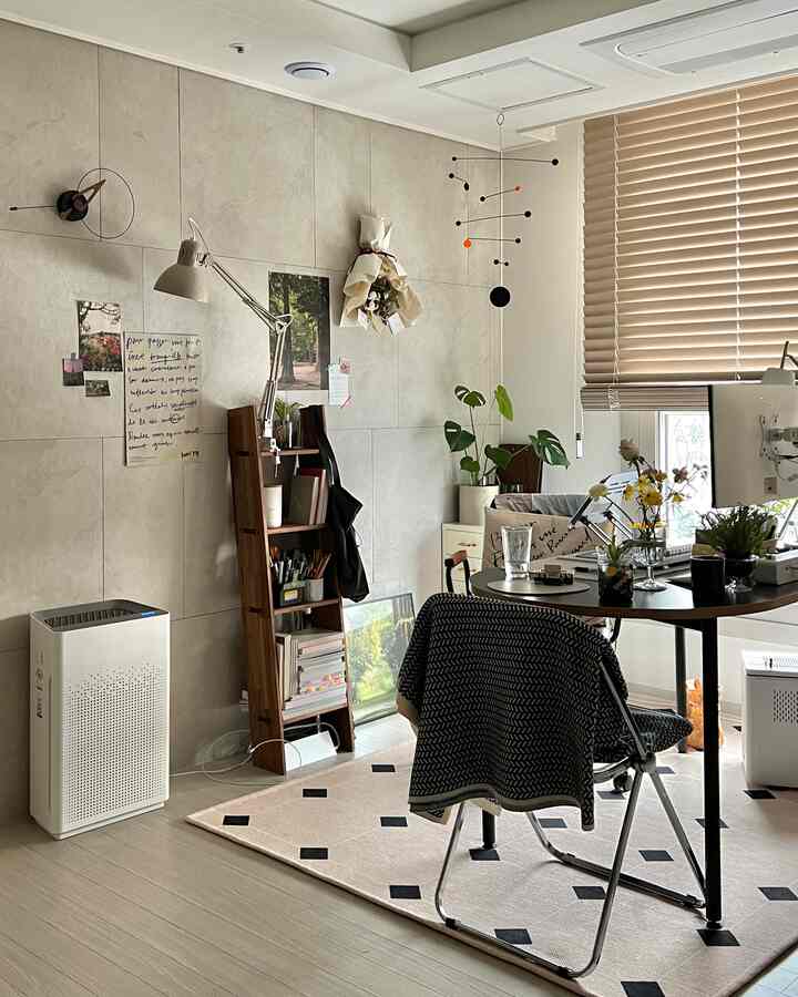 Beige-toned compact home office featuring blinds, modern furniture, and small plants in a cozy living-room style workspace