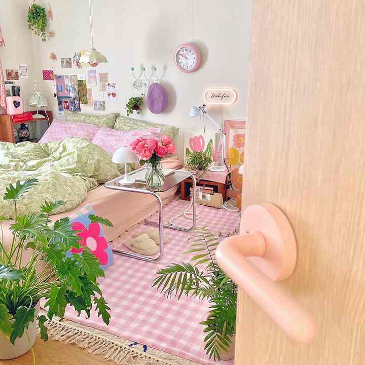 Cozy bedroom in pink and green tones featuring floral bedding and plants with a warm atmosphere