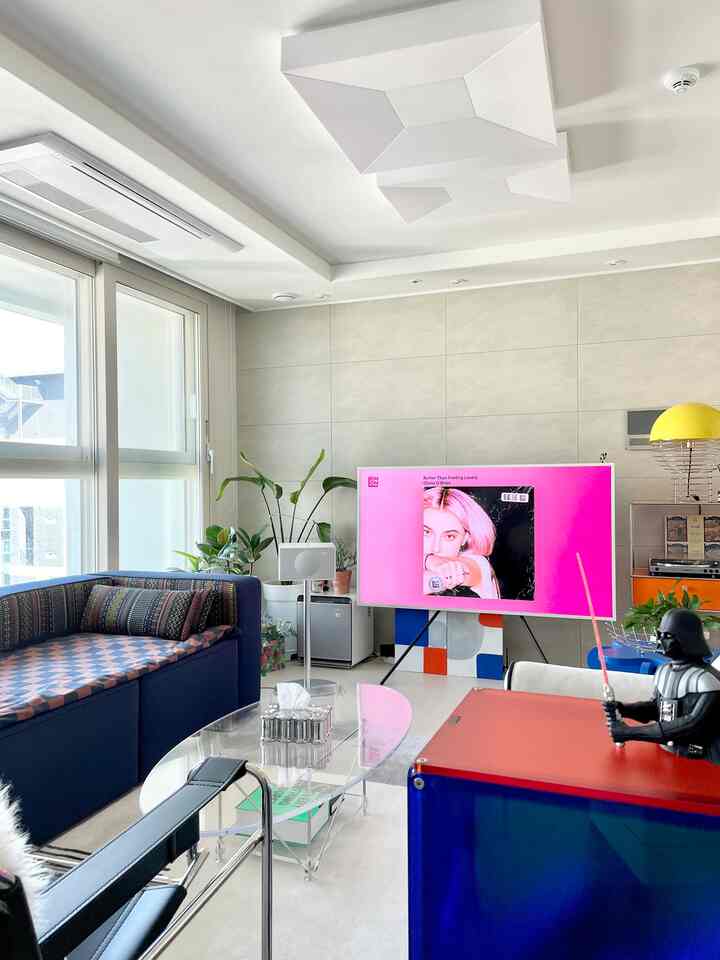 Modern living room with white walls and navy sofa, featuring a large TV and unique decorative elements