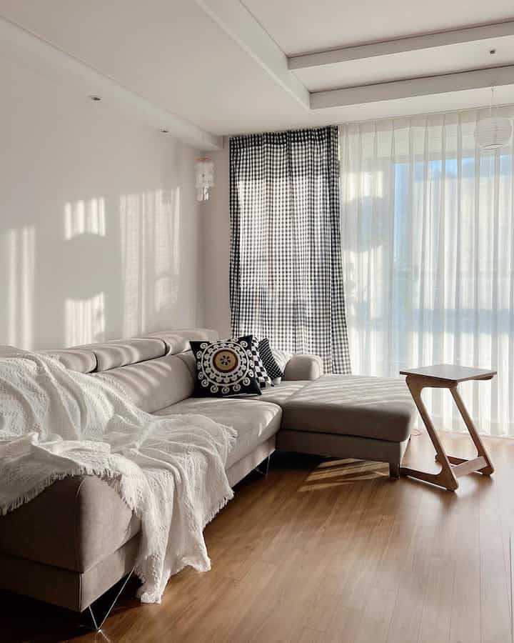Natural modern living room with beige sofa, checkered curtains, and bright wood tone flooring