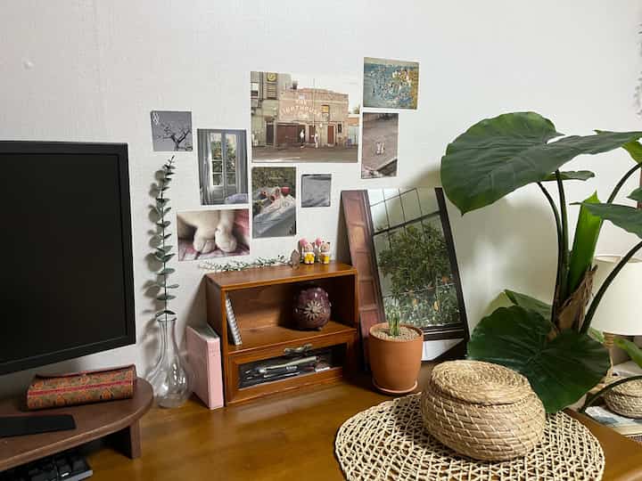 ナチュラルな木目調のテーブルと大きな植物が配置された白い壁の落ち着いたリビング