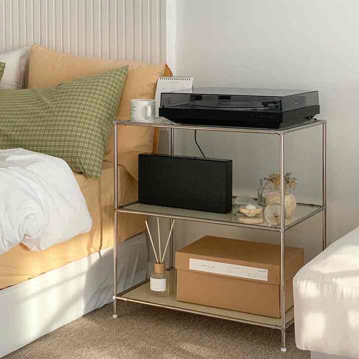 Beige and white toned bedroom with a metal nightstand and a Bluetooth turntable, creating a clean and modern atmosphere