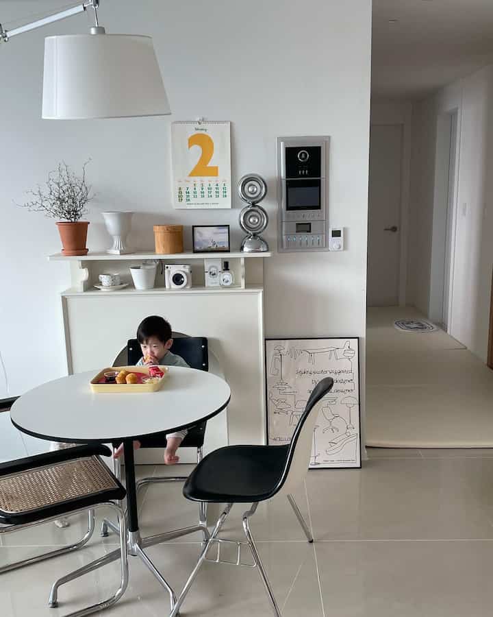 ホワイトとブラックのトーンでまとめられたミッドセンチュリーモダンダイニングルーム、テーブルで食事する赤ちゃんとナチュラルなアクセサリーが配置された印象的な空間