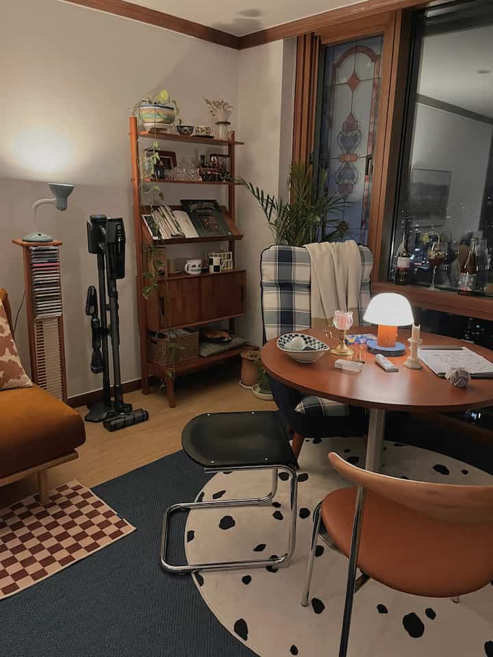 Natural wood tones and white-walled living room featuring a round dining table and checkered chair in a cozy space