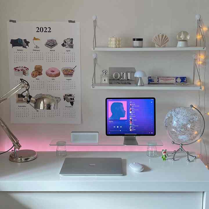 White-toned home office space featuring a clean desk with iPad Pro and various decorative items in a modern interior