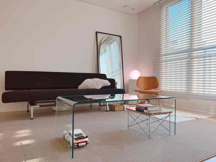 A simple modern living room with white walls, wood tone chair, and a black sofa