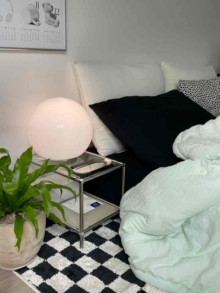 White and black toned bedroom featuring cozy bedding and a round lamp on a nightstand, creating a simple modern atmosphere