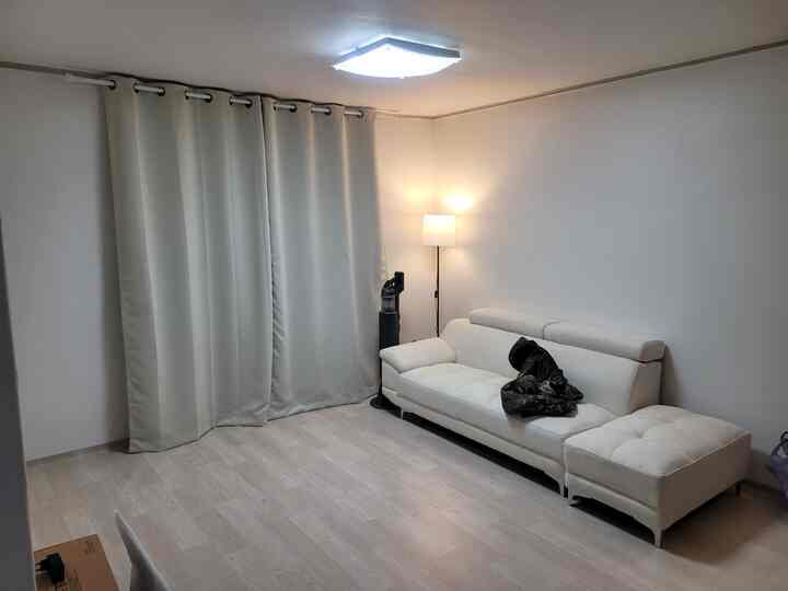 White and natural tone living room featuring sofa, blackout curtains, and floor lamp in a simple modern space