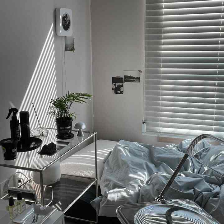 ホワイトとグレーのトーンのワンルーム寝室、メタルシェルフと植物が配置された雰囲気のある空間