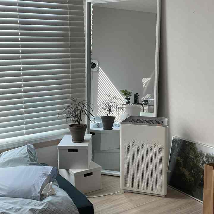 Cozy bedroom with gray blinds, white storage boxes, and an air purifier arranged neatly
