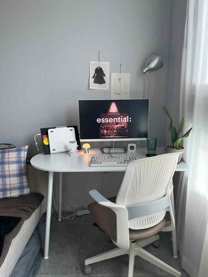 Light gray wall and white desk with office chair in a studio apartment home office space