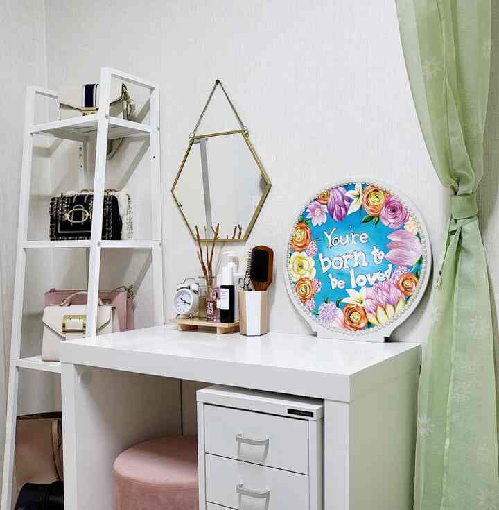 White-toned walk-in closet vanity space featuring a hexagonal wall mirror and pink stool, neat and cozy interior.