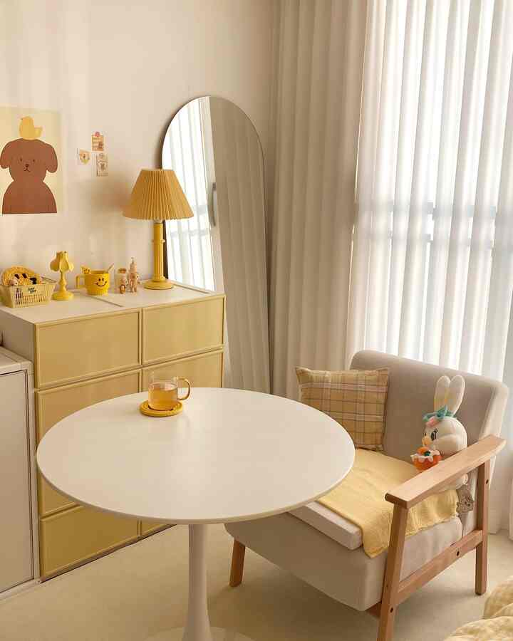 黄色と白の色調のリビング、黄色のチェストとランプ、ベージュのソファがシンプルでナチュラルな雰囲気のインテリア