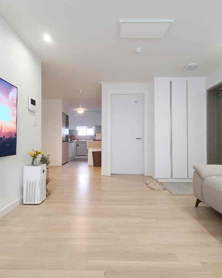 明るい木目調の床と白い壁が調和した、コンパクトで清潔感のあるリビングとキッチンの空間