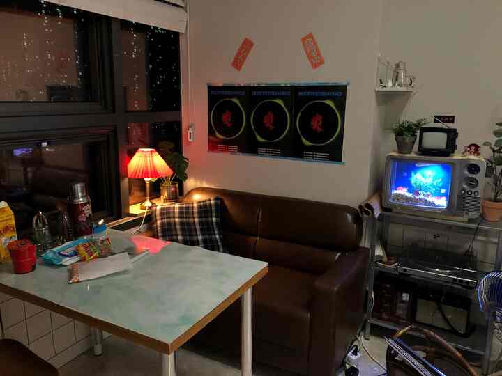 Cozy living room and dining area featuring a brown leather sofa, vintage electronics, and a red lamp