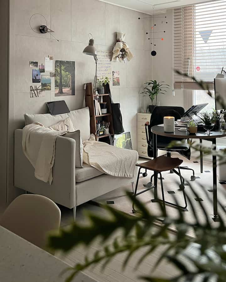 Natural modern living room and home office featuring a white sofa, round table, plants with cozy and bright atmosphere