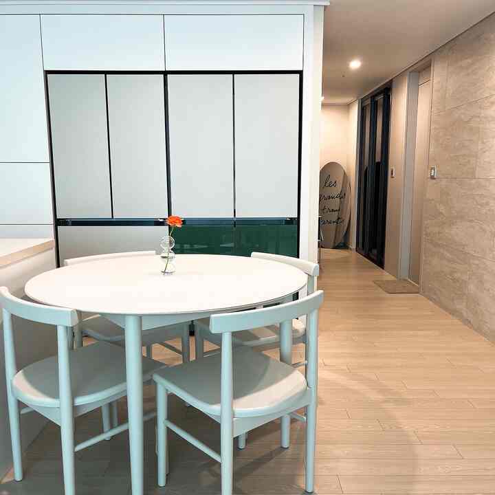 White and green accented kitchen featuring a round dining table and chairs in a clean, simple setting