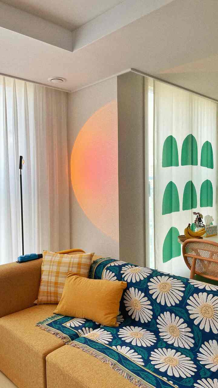 Vintage-style living room with mustard yellow sofa, blue floral throw blanket, soft curtains, and warm sunset lighting