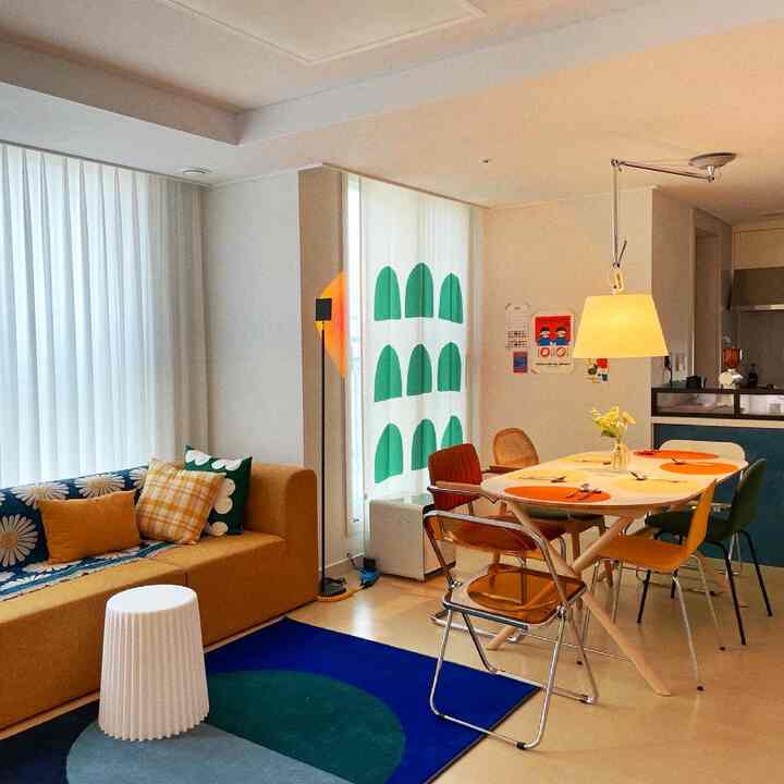 Natural-tone living and dining room featuring a yellow sofa and colorful dining chairs with a cozy, modern atmosphere