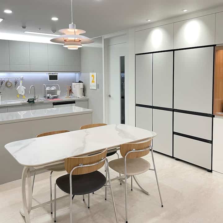 White and gray toned kitchen featuring a dining table for four in a clean, modern space