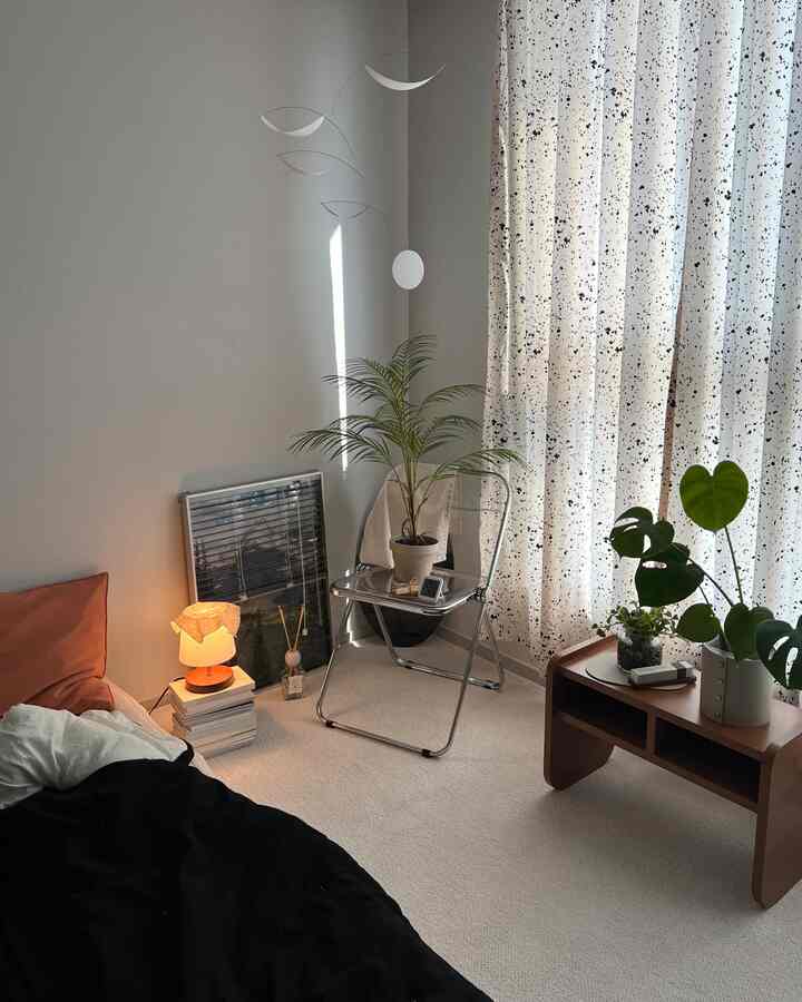 ベージュの色調の小さなリビングルーム、折りたたみ椅子とナチュラルなサイドテーブル、多彩な植物が配置された温かみのある空間