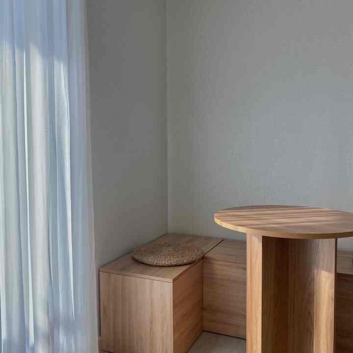 ベージュの壁と木目調の収納ベンチが配置された、小さなホームカフェの印象的な空間