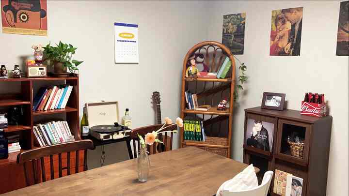 暖かいブラウン色調のヴィンテージ風リビング、本棚とラタンキャビネット、壁にヴィンテージポスターが配置された雰囲気のあるインテリア