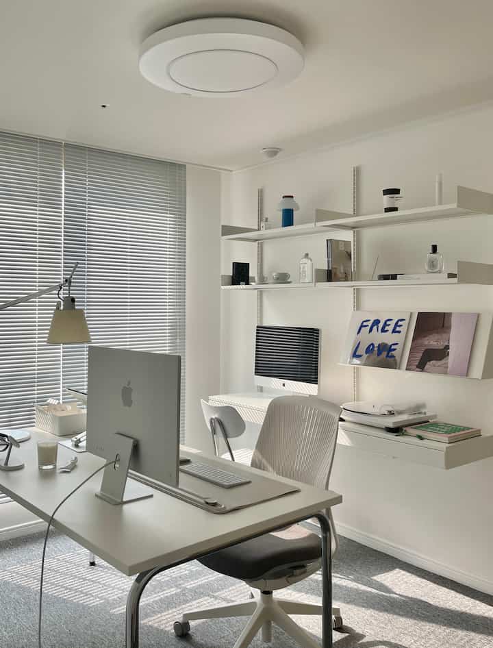 White-toned home office featuring an iMac and wall shelves in a clean and modern workspace