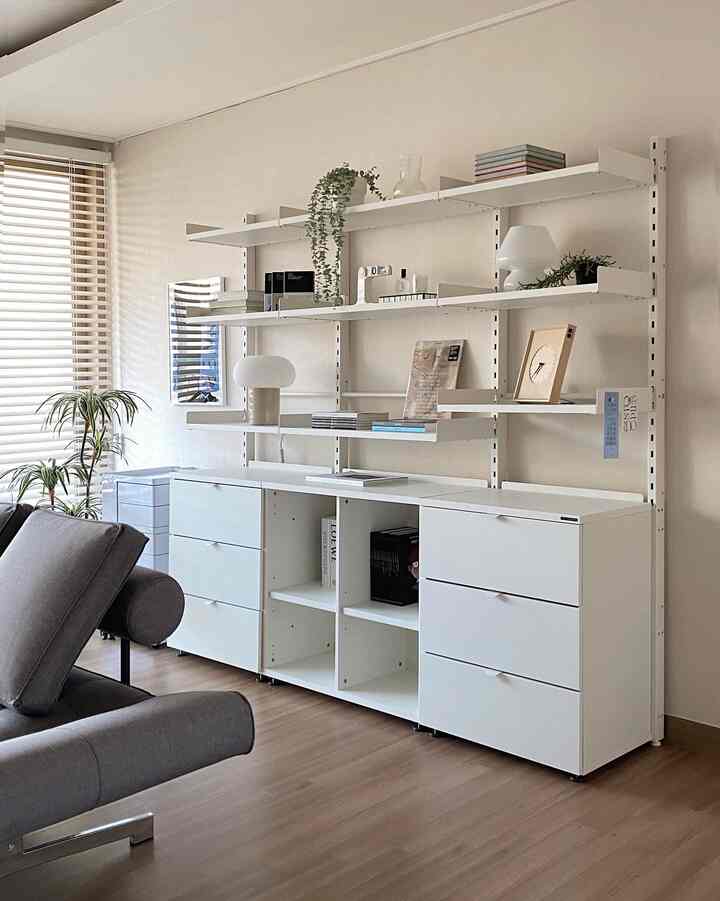 White and wood tone living room featuring modern storage units and a gray sofa, creating a cozy and clean atmosphere