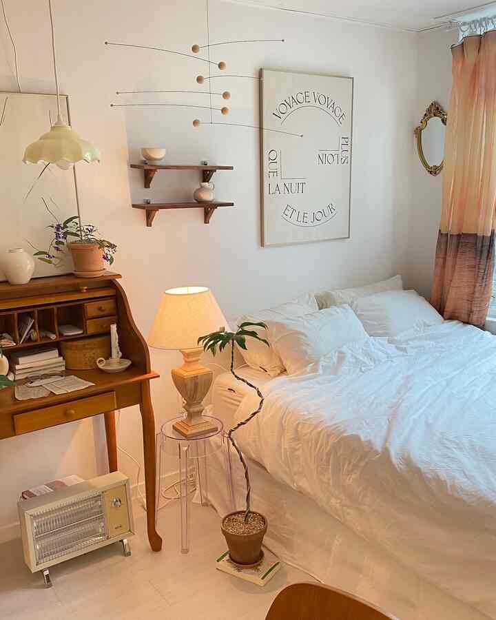 White and natural brown toned studio bedroom featuring vintage desk, lighting, and cozy atmosphere