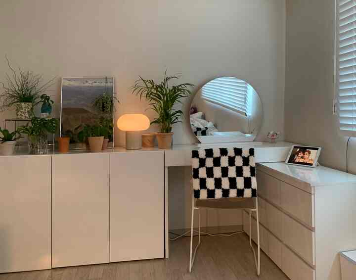 Small room vanity space in white and natural tones, featuring a round mirror and plants with a simple, clean interior design