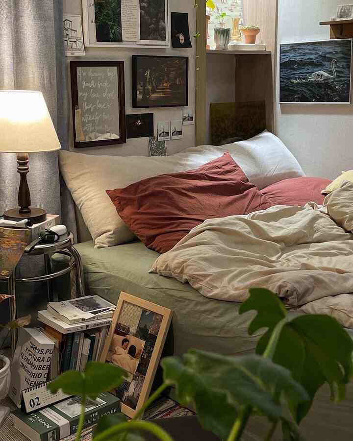 ベージュとグリーンのトーンが特徴のワンルーム寝室、ポスターと植物が配置された居心地の良い空間